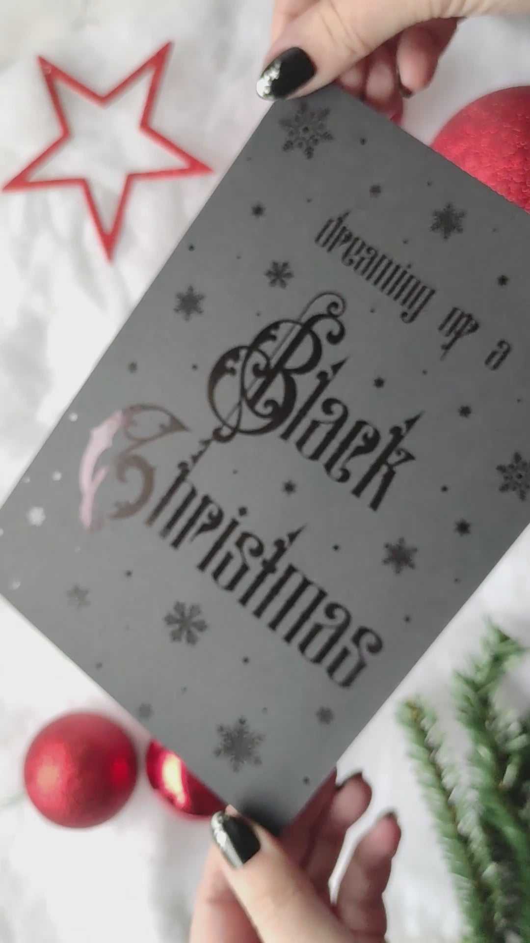 A5 handmade black Christmas card with black foil snowflakes and gothic lettering reading “Dreaming of a Black Christmas”. Portrait format on smooth black card with red interior. Includes red envelope. Blank inside.